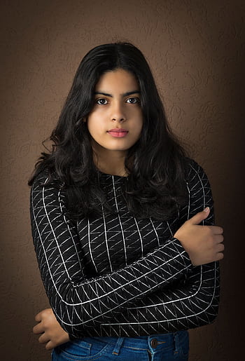 Close-up portrait of a confident young woman with long dark hair wearing casual attire indoors. HD phone wallpaper