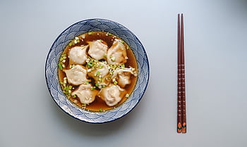 Top view of a bowl of dumplings in soup garnished with scallions. HD wallpaper