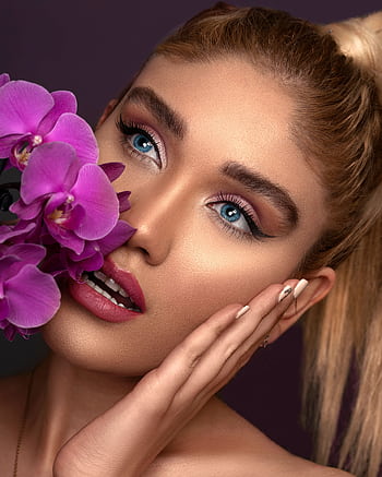 Close-up portrait of a woman with blue eyes, purple orchids, and stylish makeup. HD phone wallpaper