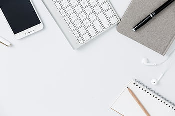 Flat lay of a modern minimalist office workspace featuring gadgets and stationery on a white table. HD wallpaper