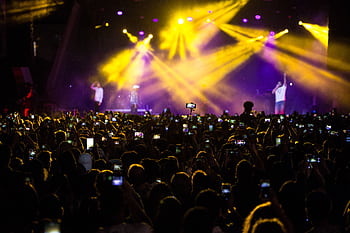 A lively concert scene with a large crowd capturing the moment with s amidst dramatic lighting. HD wallpaper