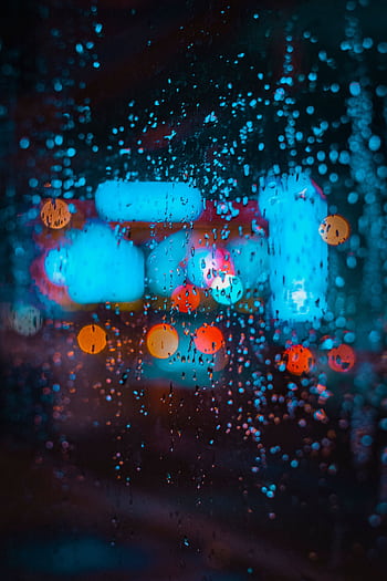 Colorful city lights creating bokeh effect through raindrops on a window. HD phone wallpaper