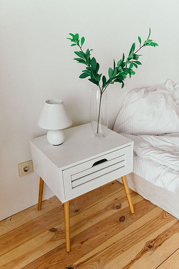 A stylish bedroom showcasing a white nightstand with a vase and lamp, perfect for modern interior design inspiration. HD phone wallpaper