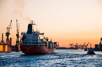 Stunning sunset view of cargo ships and cranes at the Port of Hamburg, epitomizing global trade and logistics. HD wallpaper
