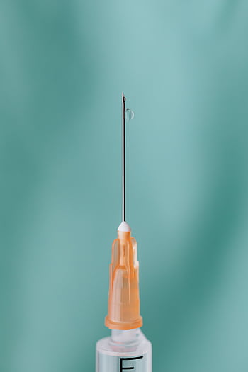 Detailed view of a syringe needle with a liquid drop, symbolizing medical care. HD phone wallpaper