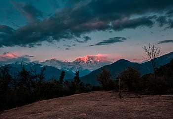 Breathtaking view of snowcapped mountains glowing under a twilight sky with rich cloud formations. HD wallpaper