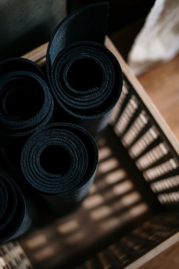 Close-up of rolled yoga mats in a basket at a fitness studio, ideal for yoga or pilates. HD phone wallpaper