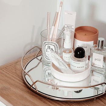 Stylish arrangement of beauty products on a wooden table with a mirror tray, creating an aesthetic display. HD phone wallpaper