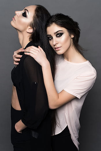 Stylish portrait of two women showcasing makeup and fashion in a studio setting. HD phone wallpaper
