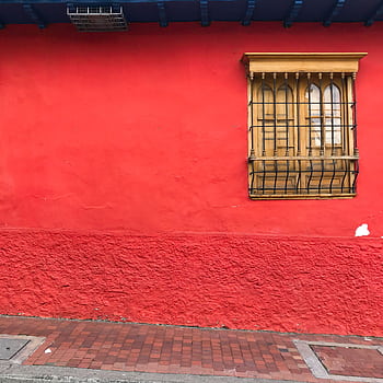 Bright red wall with a classic wooden window in Bogotá, Colombia. Urban street scene with rustic charm. HD phone wallpaper