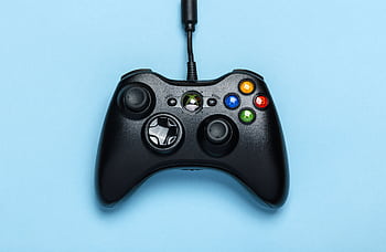 Black video game controller isolated on a blue background for gaming enthusiasts. HD wallpaper