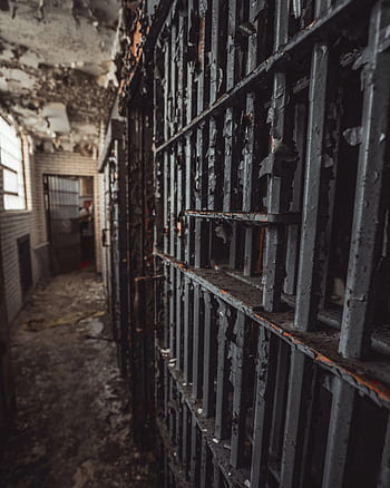 Eerie abandoned prison corridor with decaying rusty bars and peeling paint. HD phone wallpaper