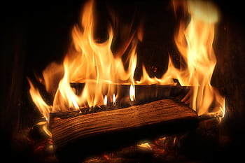 Close-up of a cozy fireplace with vibrant flames and firewood for warmth. HD wallpaper