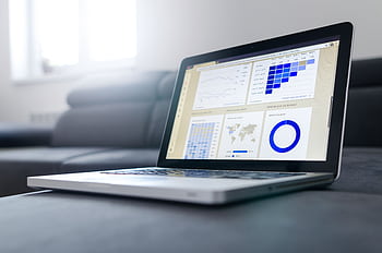 Sleek laptop showcasing data analytics and graphs on the screen in a bright room. HD wallpaper