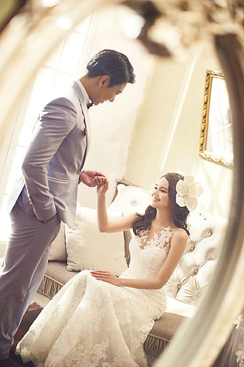 Romantic wedding couple portrait captured indoors, with bride in white dress, and groom in suit, smiling through a mirror. HD phone wallpaper