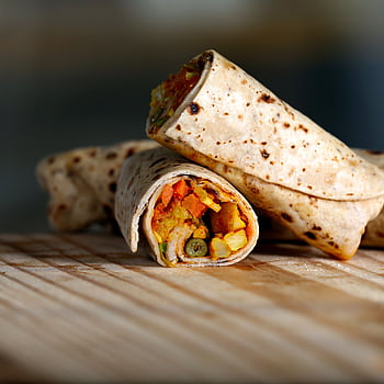 Delicious vegetarian wrap filled with colorful veggies on a wooden surface. HD phone wallpaper