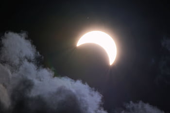 A bright crescent moon partially hidden by clouds at night, creating a dramatic celestial scene. HD wallpaper
