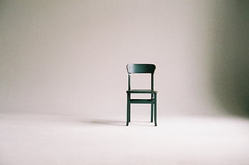 A single black chair in a minimalistic studio setting with a neutral backdrop. HD wallpaper