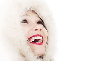 A woman with vibrant red lips and a fur hood smiles joyfully, looking upward. HD wallpaper