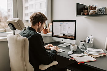 A man in a home office setting working on a computer with a relaxed and focused atmosphere. HD wallpaper