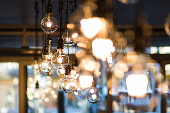 A modern and ambient urban setting with glowing, hanging light bulbs in focus. HD wallpaper