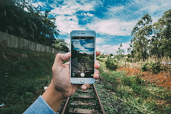 A person captures a scenic railway landscape using a smart outdoors. HD wallpaper