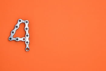 A creative design of the number four formed with a metal chain against an orange background, offering ample copy space. HD wallpaper
