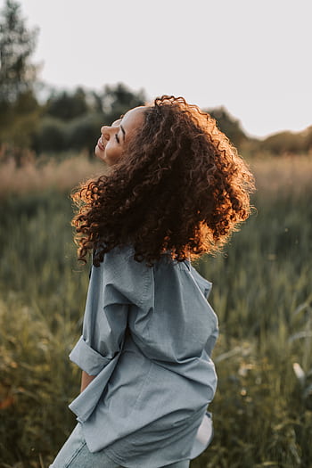 A care woman enjoying nature, showcasing happiness and dom in a sunlit field. HD phone wallpaper