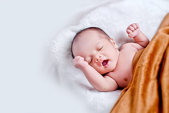 A peaceful sleeping infant wrapped in a soft, warm blanket on a cozy white surface. HD wallpaper