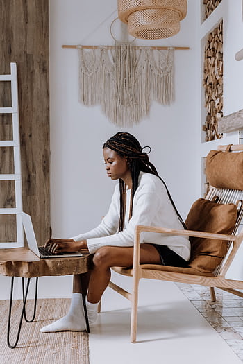 African American woman using a laptop in a cozy, modern Scandinavian-style apartment. HD phone wallpaper