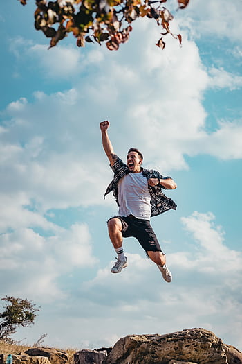 A vibrant of a young man jumping with joy outdoors, capturing a moment of dom and exhilaration. HD phone wallpaper
