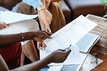 Group of professionals reviewing documents during an office meeting, emphasizing teamwork and strategy. HD wallpaper