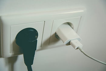 A close-up view of a wall outlet with two plugs inserted, capturing the simplicity of electrical connectivity. HD wallpaper