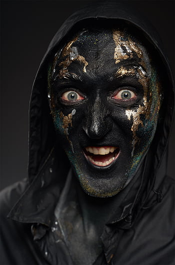 A close-up portrait of a person wearing a creepy black and gold face mask for Halloween. HD phone wallpaper