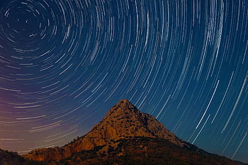 Capturing the mesmerizing star trails over a mountain in Antalya, Turkey under a clear night sky. HD wallpaper