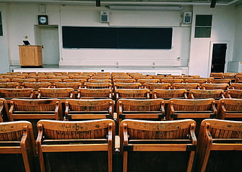 An empty lecture hall featuring wooden chairs and a large blackboard. HD wallpaper