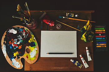 Vibrant artist workspace with paintbrushes, palette, paint tubes, and blank canvas. HD wallpaper