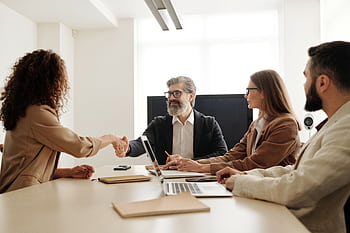 Colleagues in an office celebrating a successful negotiation with a handshake. HD wallpaper