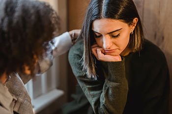 A woman comforts a friend experiencing sorrow, providing emotional support indoors. HD wallpaper