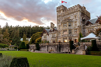 Historic Hatley Castle in Victoria, BC, at sunset, showcasing its stunning architecture and lush gardens. HD wallpaper