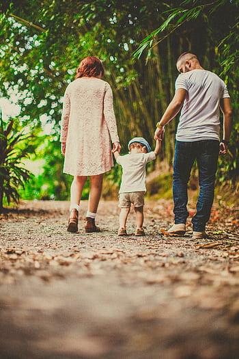 A family enjoys a leisurely walk in a green park, embodying joy and togetherness. HD phone wallpaper
