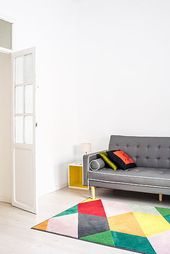 Stylish minimalist living room featuring a colorful geometric rug and a cozy grey sofa for a chic home interior. HD phone wallpaper