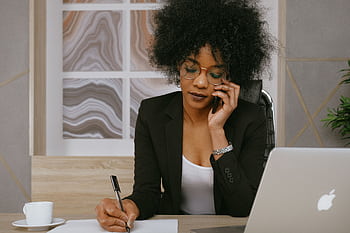 Businesswoman making a call while working at the desk, focused and professional. HD wallpaper