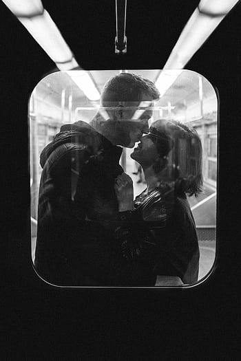 Monochrome of a couple kissing inside a subway train, creating an intimate moment. HD phone wallpaper