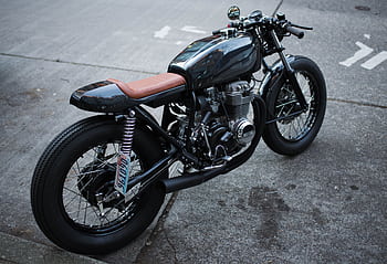Retro-style motorcycle parked on an urban street, showcasing a classic design. HD wallpaper