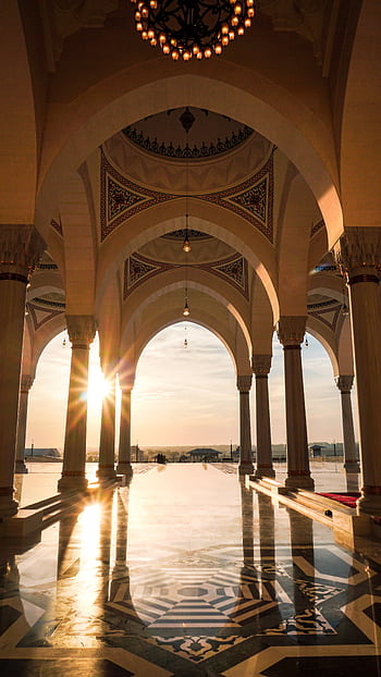 Sunlit arches inside a beautiful mosque interior showcasing Islamic architecture at sunset. HD phone wallpaper