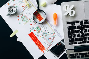 Top view of financial documents, charts, and laptop organized on a desk. HD wallpaper