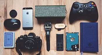 Flat lay of various modern gadgets, accessories, and tech items on wooden surface. HD wallpaper