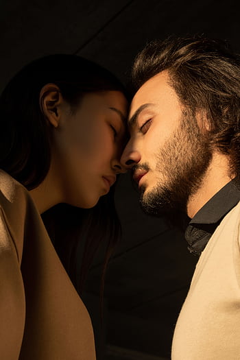 Side view of a couple sharing an intimate moment with closed eyes under soft lighting. HD phone wallpaper