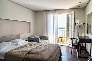 Spacious, elegantly furnished hotel room featuring a balcony with a sea view and modern amenities. HD wallpaper